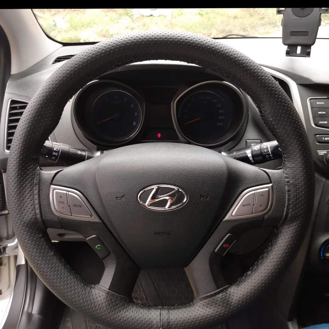 Volante de um carro da Hyundai com capa costurada e linha de costura preta.